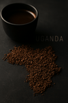 Map of Africa made from ground coffee beans with a cup of coffee on a dark background, featuring the word 'Uganda'.